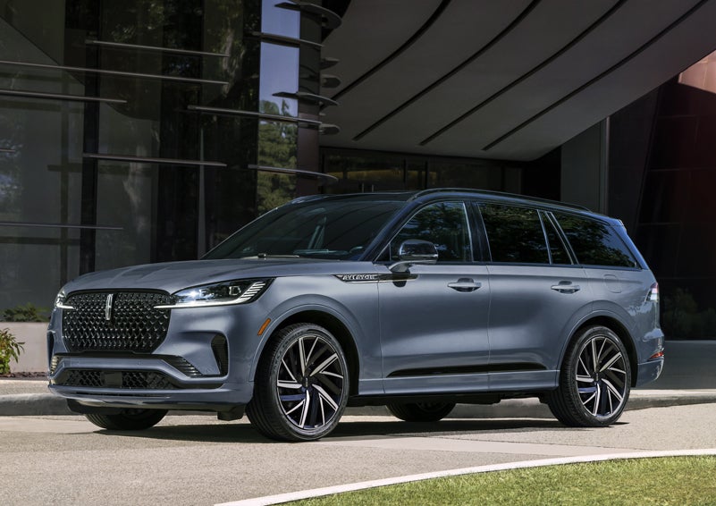 A gray 2025 Lincoln Aviator® SUV is parked outside a modern building showcasing the driver’s side of the vehicle. | Mark McLarty Lincoln in North Little Rock AR