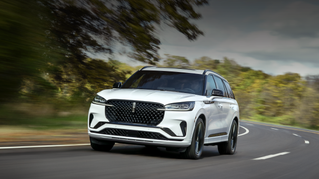 A white 2025 Lincoln Aviator® SUV is being driven down a road lined with trees. | Mark McLarty Lincoln in North Little Rock AR