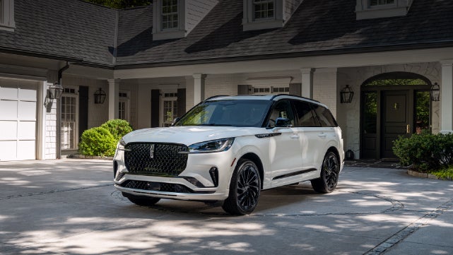 A white 2026 Lincoln Aviator® SUV is parked in the driveway of a luxury home. | Mark McLarty Lincoln in North Little Rock AR