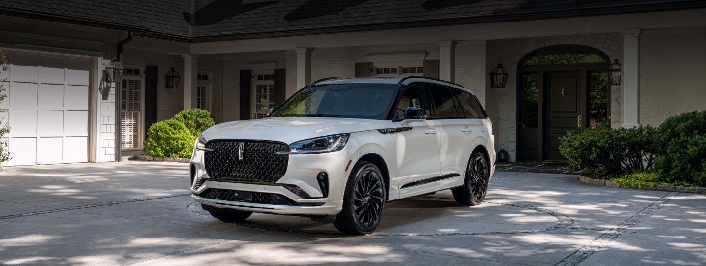 A white 2026 Lincoln Aviator® SUV is parked in the driveway of a luxury home. | Mark McLarty Lincoln in North Little Rock AR