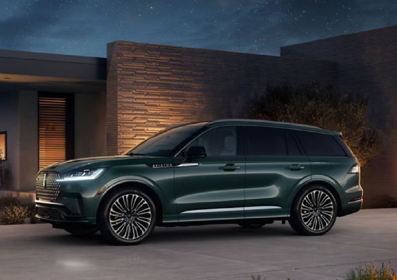 A green 2027 Lincoln Aviator® SUV is parked outside a contemporary home. | McLarty Lincoln in North Little Rock AR
