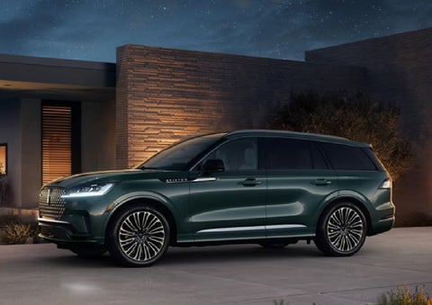 A green 2027 Lincoln Aviator® SUV is parked outside a contemporary home. | McLarty Lincoln in North Little Rock AR