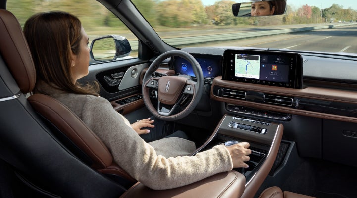 A 2027 Lincoln Aviator® SUV is being driven hands-free on a highway lined with trees. | McLarty Lincoln in North Little Rock AR